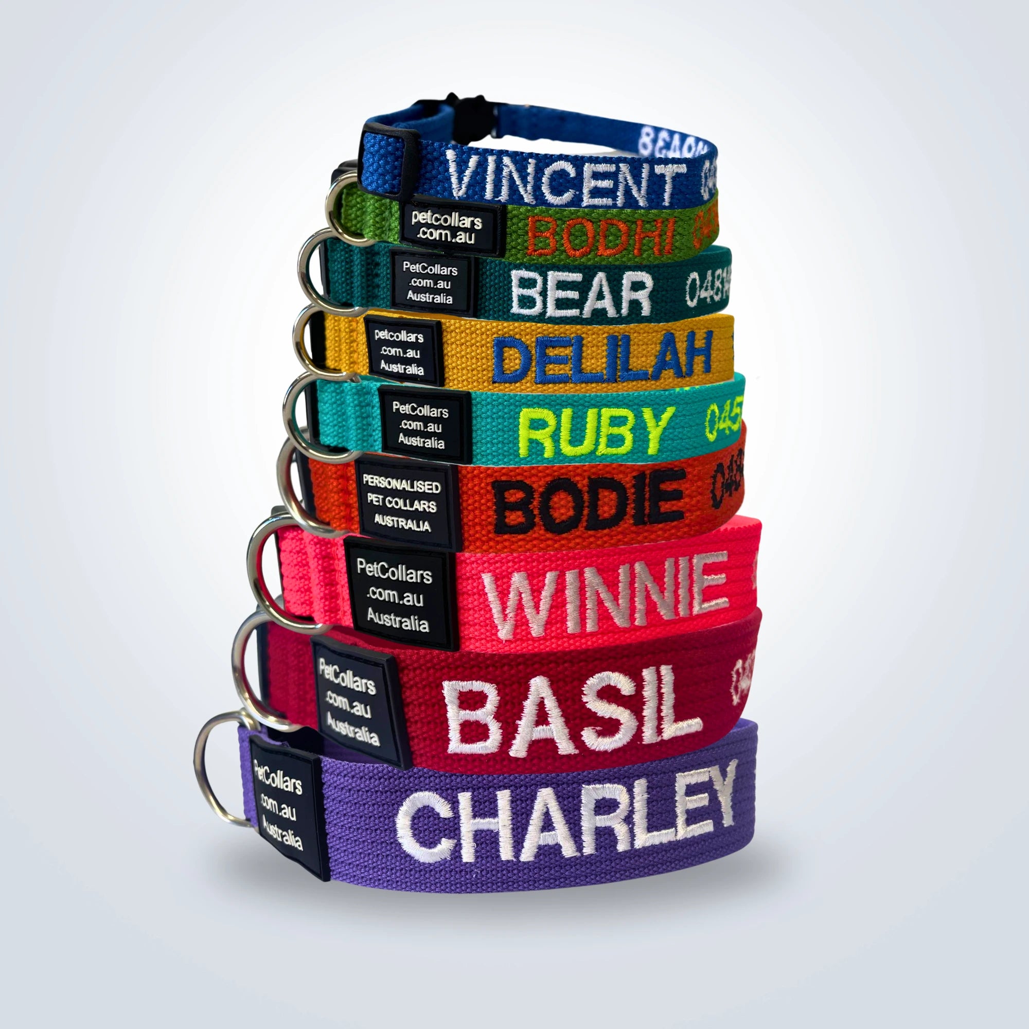 A stack of personalised pet collars in every size, each embroidered with a dog's name